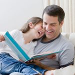 Hispanic father reading book to daughter